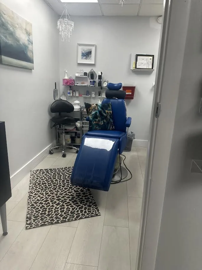 The treatment room: a blue reclining treatment chair beside a rolling stool, a supply cart and shelves of supplies
